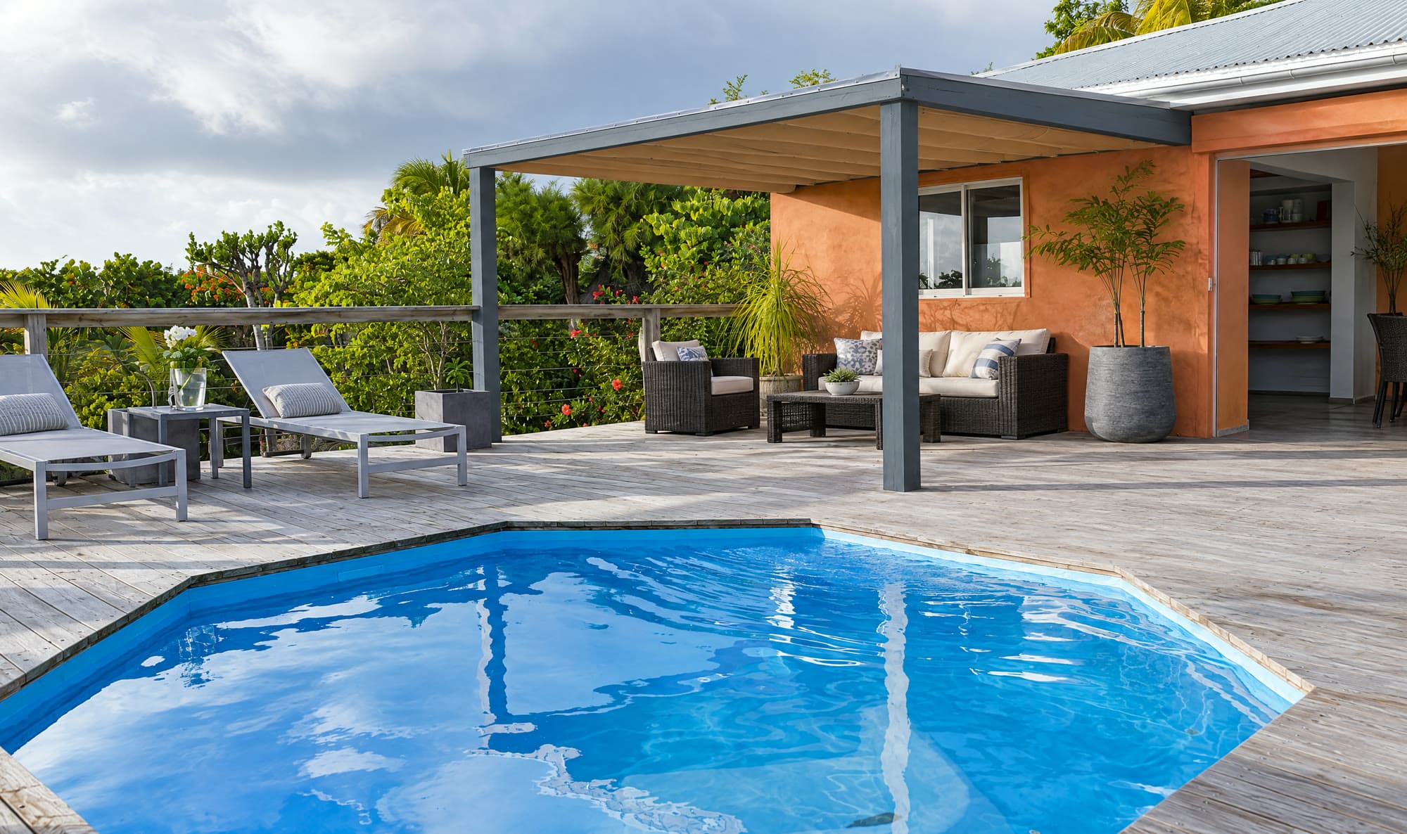 The plunge pool in front of the coral villa and its slate-grey pergola
